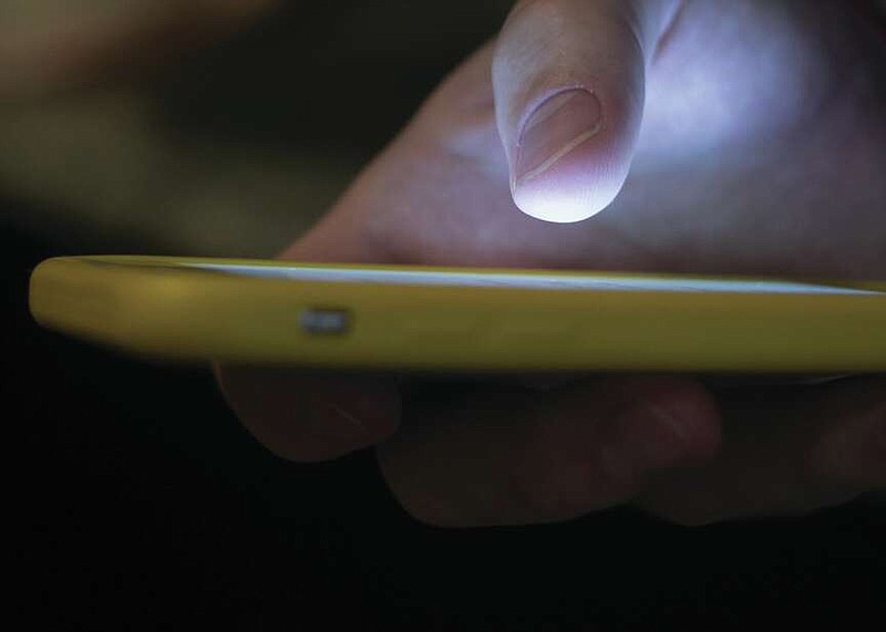 FILE - A man uses a cellphone in New Orleans, Aug. 11, 2019.  (AP Photo/Jenny Kane, File)