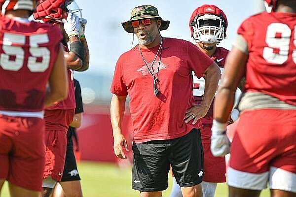 Arkansas defensive line coach Deke Adams (center) instructs players during a drill Aug. 11 during practice at the Fred W. Smith Football Center in Fayetteville.