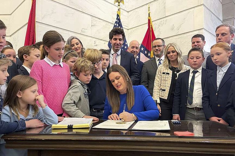 FILE - Arkansas Gov. Sarah Huckabee Sanders signs an education overhaul bill into law on March 8, 2023, at the state Capitol in Little Rock, Ark. Four Arkansas residents filed a lawsuit on Friday, June 7, 2024, challenging the school voucher program created by the bill, saying it violates the state constitution's protections for educational funding. (AP Photo/Andrew DeMillo, File)