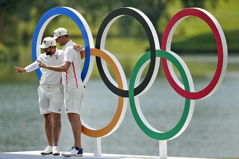 Matthieu Pavon, left, and Victor Perez, of France, pose for a photo under the Olympic rings during a practice round for the men's golf event at the 2024 Summer Olympics, Wednesday, July 31, 2024, at Le Golf National in Saint-Quentin-en-Yvelines, France. (AP Photo/Matt York)