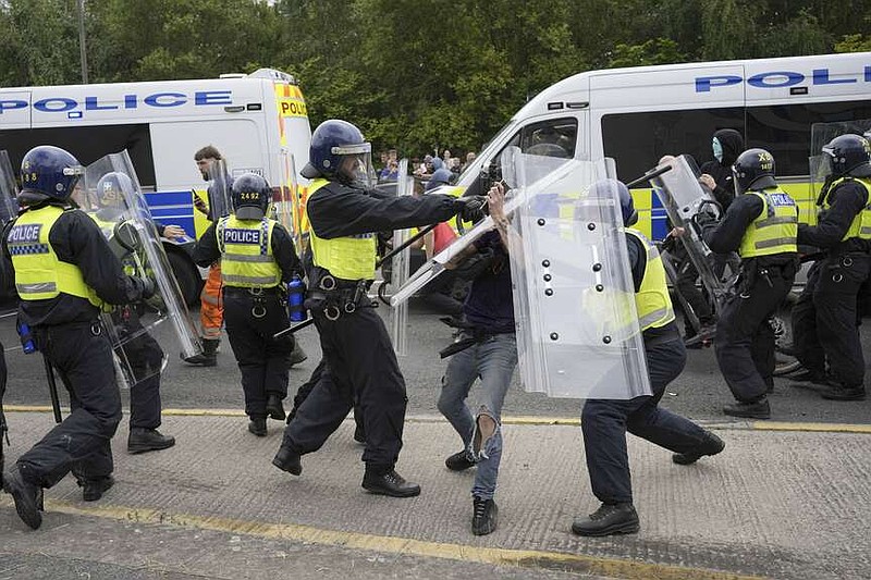 Police officers with protesters as trouble flares during an anti-immigration protest outside the Holiday Inn Express in Rotherham, England, Sunday Aug. 4, 2024. (Danny Lawson/PA via AP)