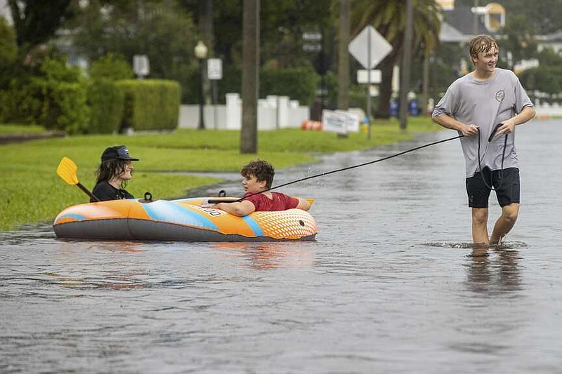 Landon Stanley pulls his friends Jakob Jackson and Emerson Porcelli-Wilson in the waters flooding the streets from Tropical Storm Debby on Sunday, Aug. 4, 2024 in Tampa, Fla. (Luis Santana/Tampa Bay Times via AP)